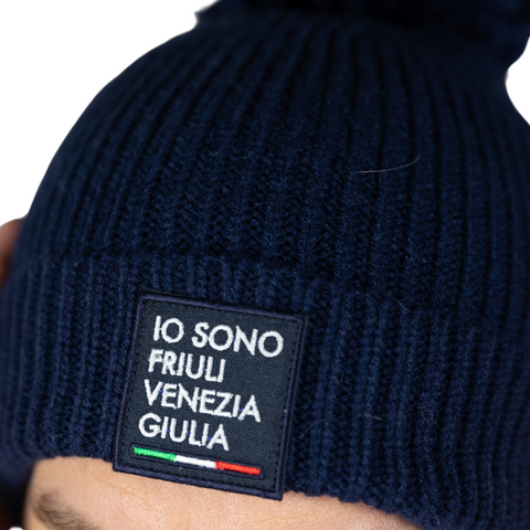 Berretto blu in primo piano con logo Io Sono Friuli Venezia Giulia e bandiera italiana