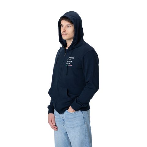 Felpa blu con zip e cappuccio con logo grande sulla manica Io Sono Friuli Venezia Giulia indossata da un ragazzo su sfondo bianco