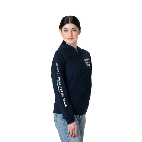 Felpa blu con cappuccio e zip con logo grande sulla manica Io Sono Friuli Venezia Giulia indossata da una ragazza su sfondo bianco vista laterale