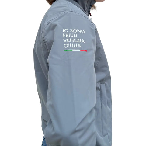 Giacca Waikato grigia impermeabile senza cappuccio con logo Io Sono Friuli Venezia Giulia sulla manica indossata da una donna su sfondo bianco