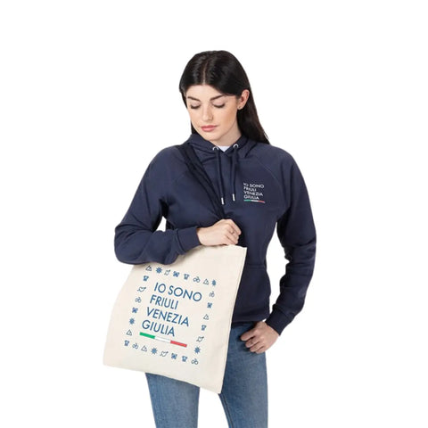 Shopper bianca indossata da una ragazza con logo Io Sono Friuli Venezia Giulia in blu e bandiera italiana.